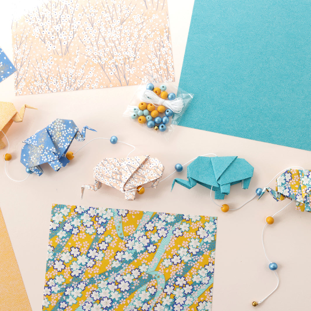 photo d'ambiance de la guirlande montée du kit guirlande d'éléphants en origami jaune safran, bleu pervenche, rose clair et bleu canard « bombay » adeline klam