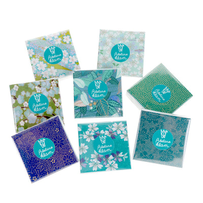 photo packshot de 100 papiers origami de 6cm par 6cm aux motifs variés dans les tons bleu turquoise, bleu canard et vert d'eau de la gamme « paon » adeline klam