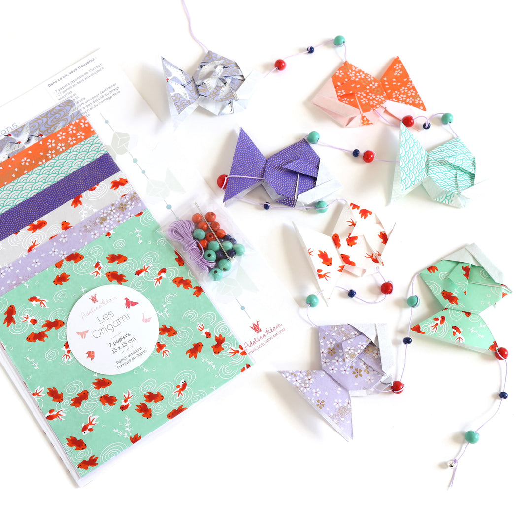 photo packshot de biais du packaging et de la guirlande montée du kit guirlande de poissons dans les tons vert d'eau, rouge orange, blanc crème et violet mauve « fluorite » adeline klam