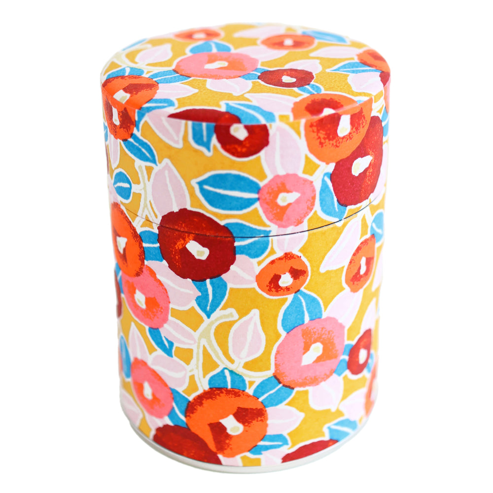 photo packshot d'une boîte à thé cylindrique fermée tapissée d'un papier japonais aux motifs de camélias dans les tons jaune moutarde, rouges, roses et bleus (M802) adeline klam