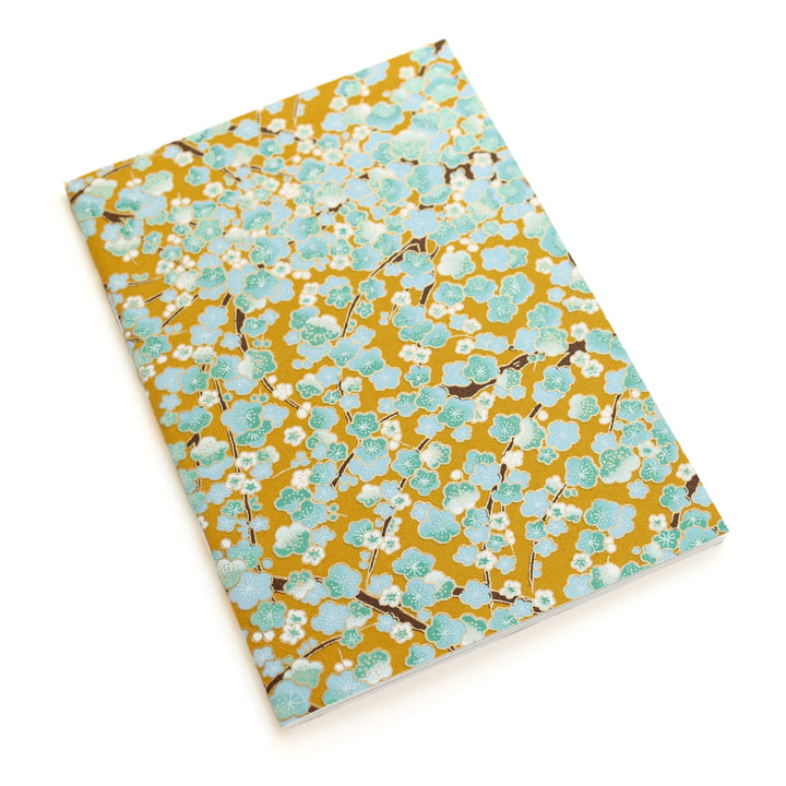 photo packshot d'un carnet habillé de papier japonais au motif de fleurs de prunier dans les tons jaune caramel, vert d'eau, bleu ciel et blancs (M450) adeline klam