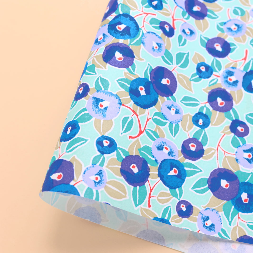photo packshot d'une courbe de papier japonais yuzen chiyogami aux motifs de camélias dans les tons bleu moyen et turquoise, violet clair et foncé et vert d'eau adeline klam (M1024)
