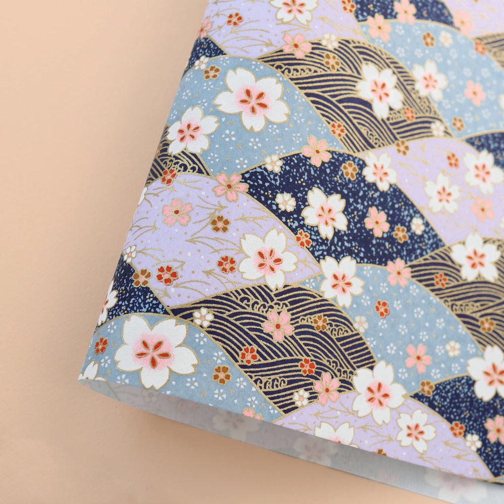 photo packshot d'une courbe de papier japonais yuzen chiyogami aux motifs de dunes, de vagues et de fleurs de cerisier dans les tons lilas, bleu gris et marine, blancs, noirs et dorés adeline klam (M1030)