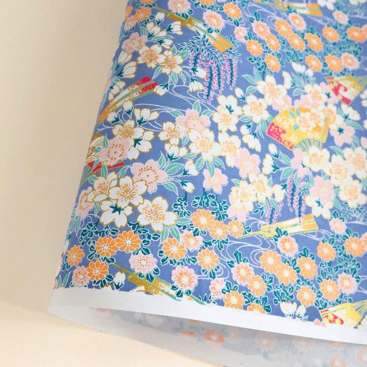 photo packshot d'une courbe de papier japonais yuzen chiyogami aux motifs de fleurs de cerisier, de chrysanthèmes, de glycines et d'éventails dans les tons bleu pervenche et canard, orange, rose pâle, vert d'eau et blancs adeline klam M1014