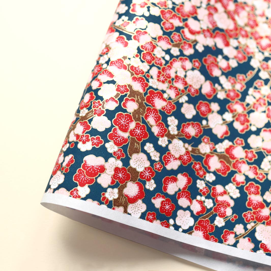 photo packshot d'une courbe de papier japonais yuzen chiyogami aux motifs de fleurs de prunier dans les tons bleu marine, rouges et roses adeline klam (M592)