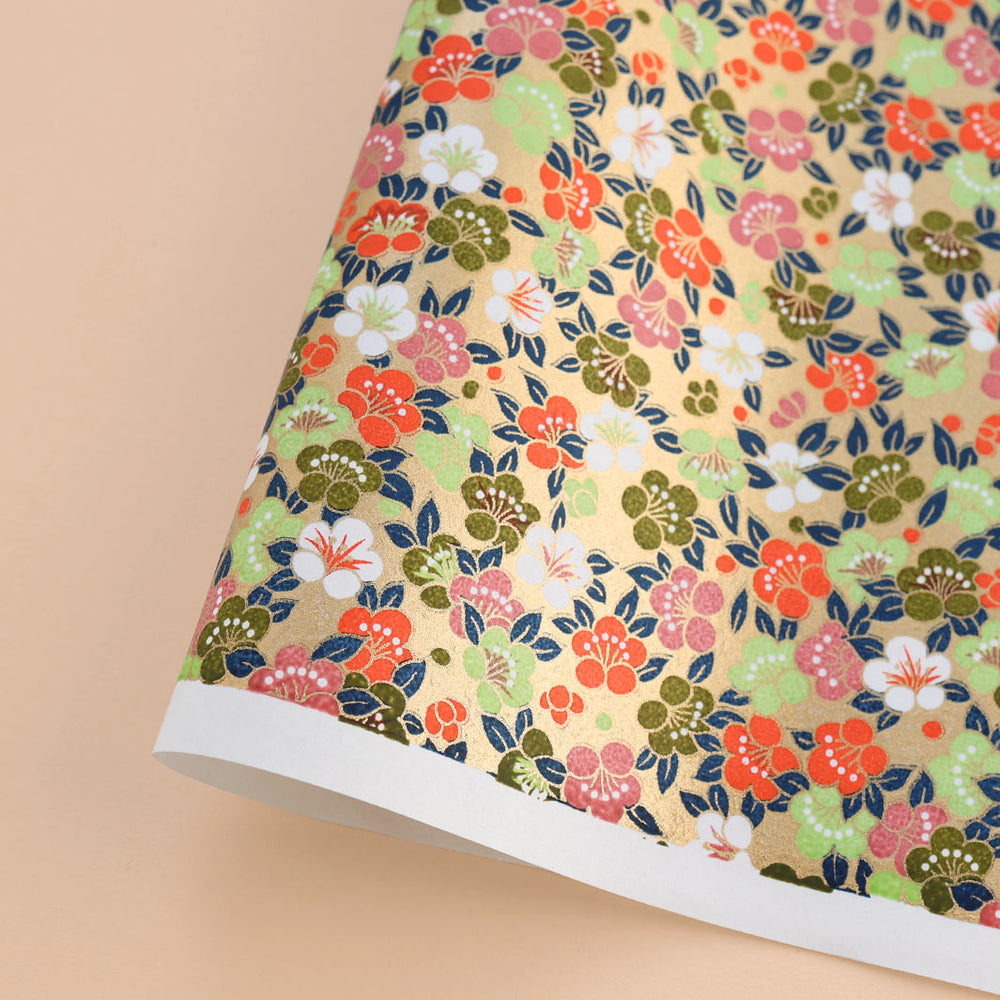 photo packshot d'une courbe de papier japonais yuzen chiyogami aux motifs de fleurs de prunier festives dans les tons dorés, rouge orange, bois de rose, vert clair et foncé, bleu marine adeline klam (M1040)