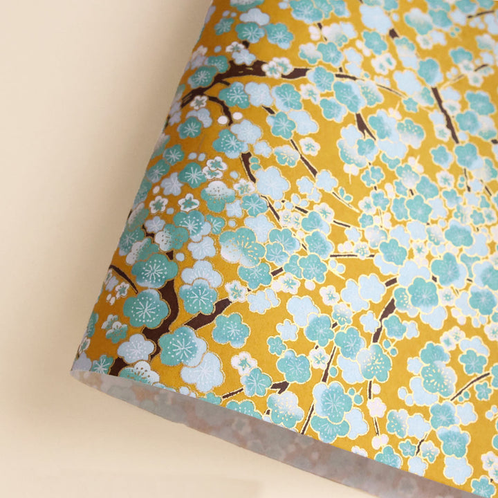 photo packshot d'une courbe de papier japonais yuzen chiyogami aux motifs de fleurs de prunier dans les tons jaune caramel, vert d'eau, bleu ciel et blancs adeline klam (M450)