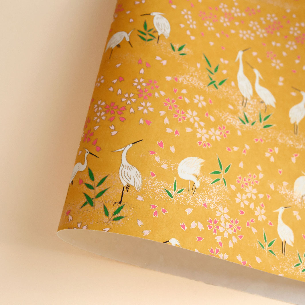 photo packshot d'une courbe de papier japonais yuzen chiyogami aux motifs de hérons et de fleurs sur fond jaune moutarde adeline klam (M659)