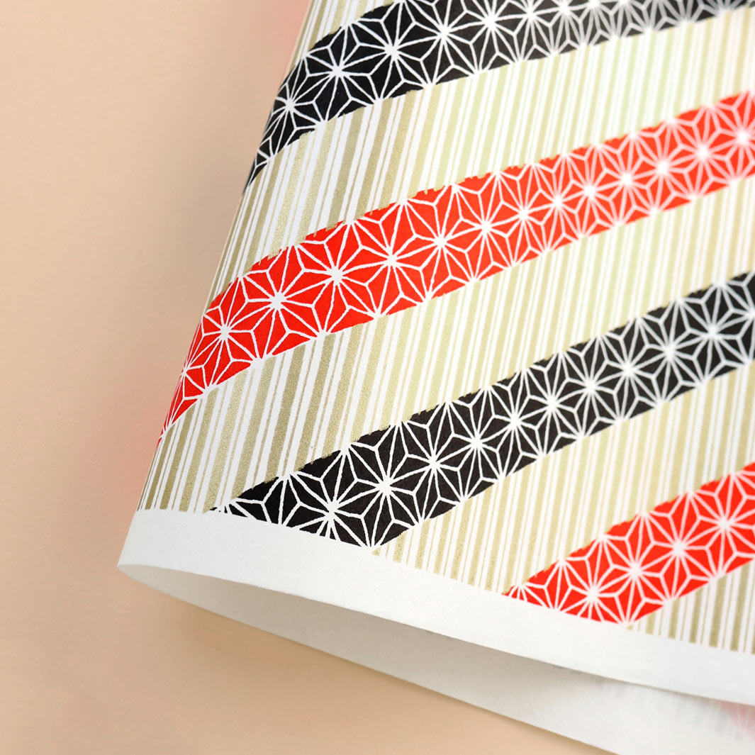 photo packshot d'une courbe de papier japonais yuzen chiyogami aux motifs de lignes épaisses et de grandes étoiles dans les tons noirs, rouges et or clair adeline klam (M1027)