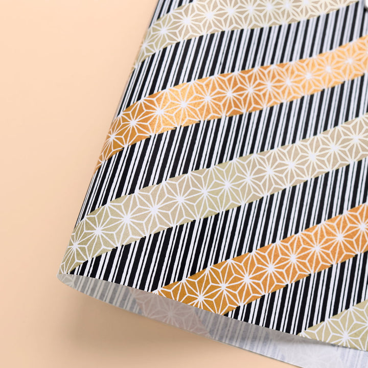photo packshot d'une courbe de papier japonais yuzen chiyogami aux motifs de lignes épaisses et de grandes étoiles dans les tons or clair, bronze et noirs adeline klam (M1023)