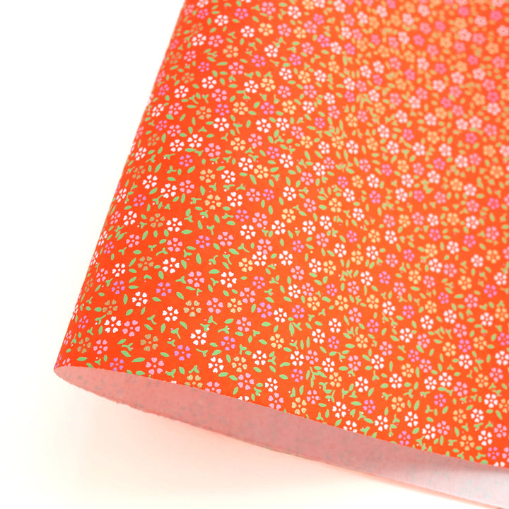photo packshot d'une courbe du papier japonais yuzen chiyogami au motif de mini fleurs de cerisier sur fond rouge orange adeline klam (M964)