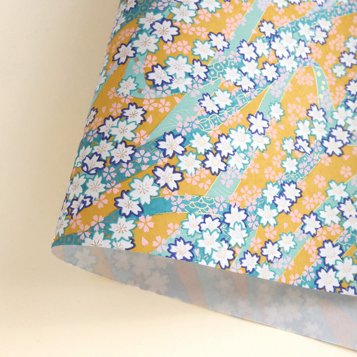 photo packshot d'une courbe de papier japonais yuzen chiyogami aux motifs d'ondulations fleuries dans les tons jaune moutarde, vert d'eau, bleu canard, violet foncé, roses et dorés adeline klam M997