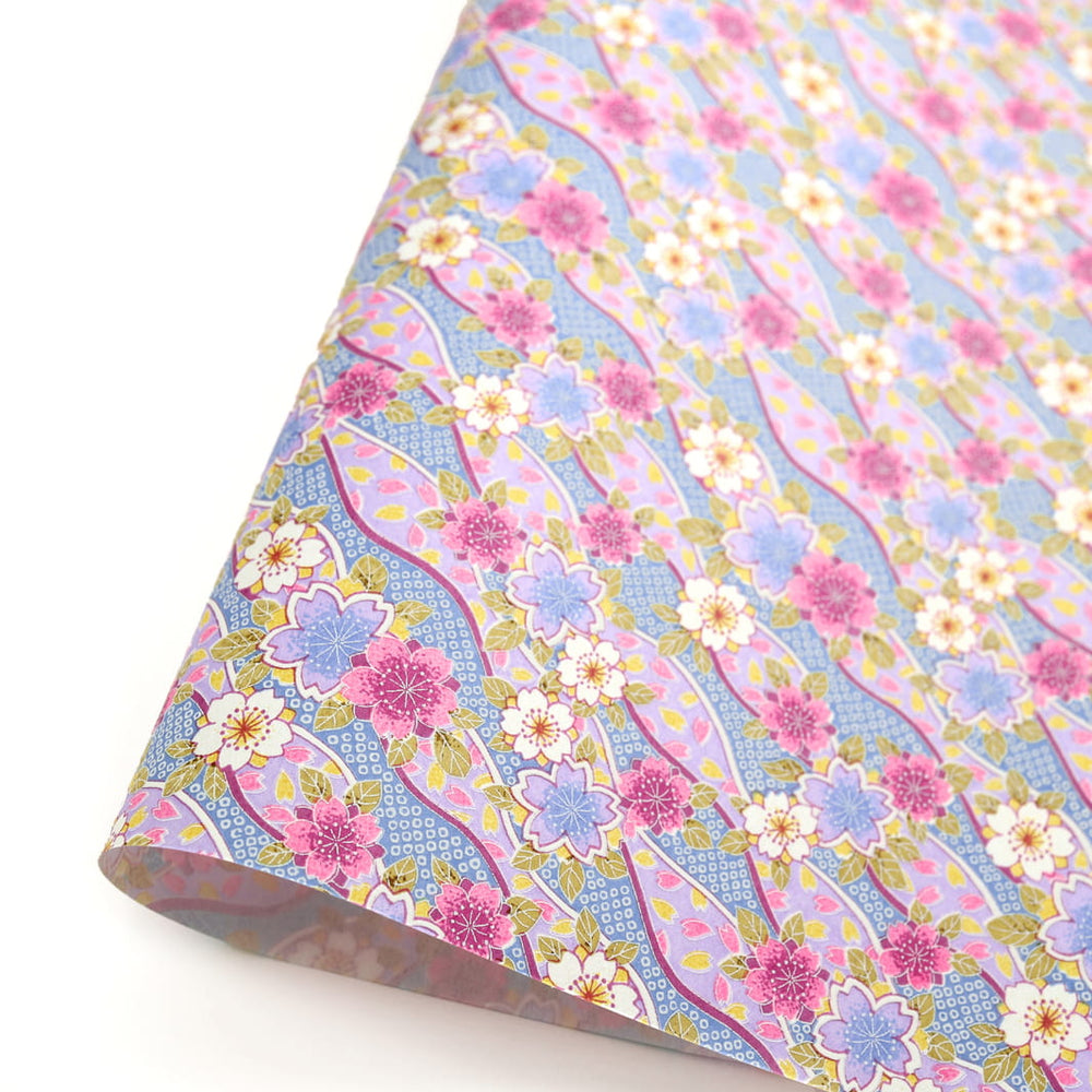 photo packshot d'une courbe de papier japonais yuzen chiyogami aux motifs d'ondulations fleuries de cerisier et de petits losanges kanoko dans les tons lilas, mauve, bleus et jaunes adeline klam (M1050)