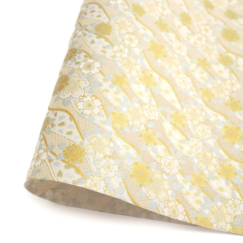 photo packshot d'une courbe de papier japonais yuzen chiyogami aux motifs d'ondulations fleuries de cerisier et de petits losanges kanoko dans les tons dorés, argentés et blancs adeline klam (M1049)
