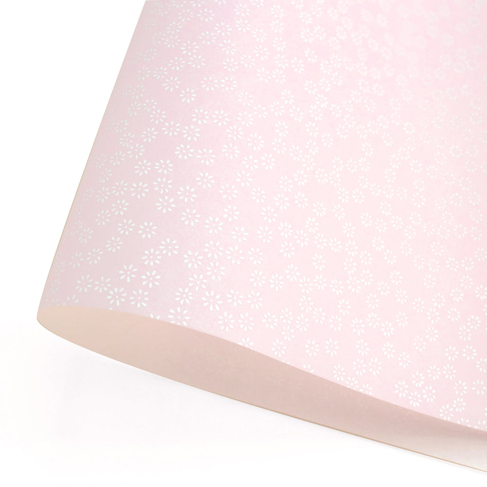 photo packshot d'une courbe de papier japonais yuzen chiyogami aux motifs de semi de fleurs blanches sur fond rose pastel adeline klam (M481)