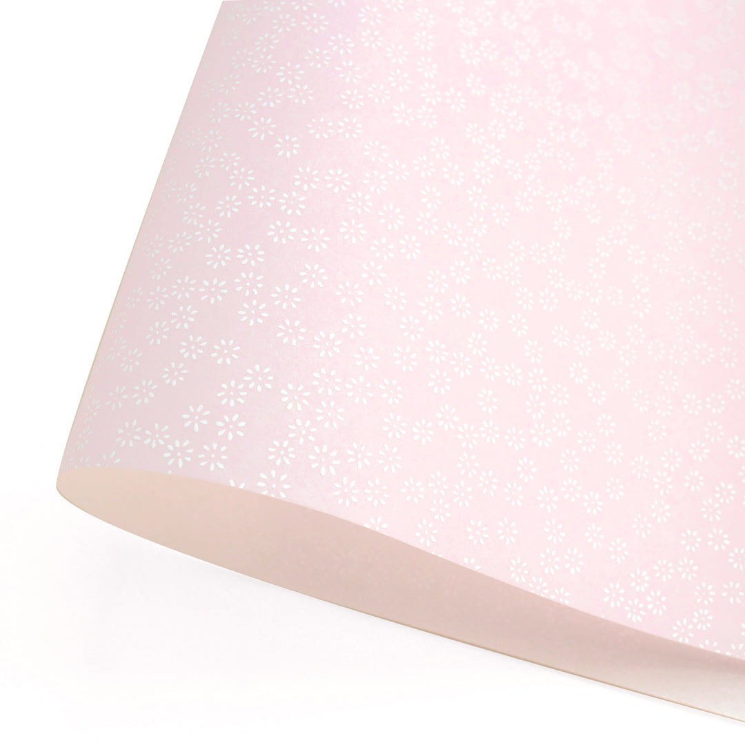 photo packshot d'une courbe de papier japonais yuzen chiyogami aux motifs de semi de fleurs blanches sur fond rose pastel adeline klam (M481)