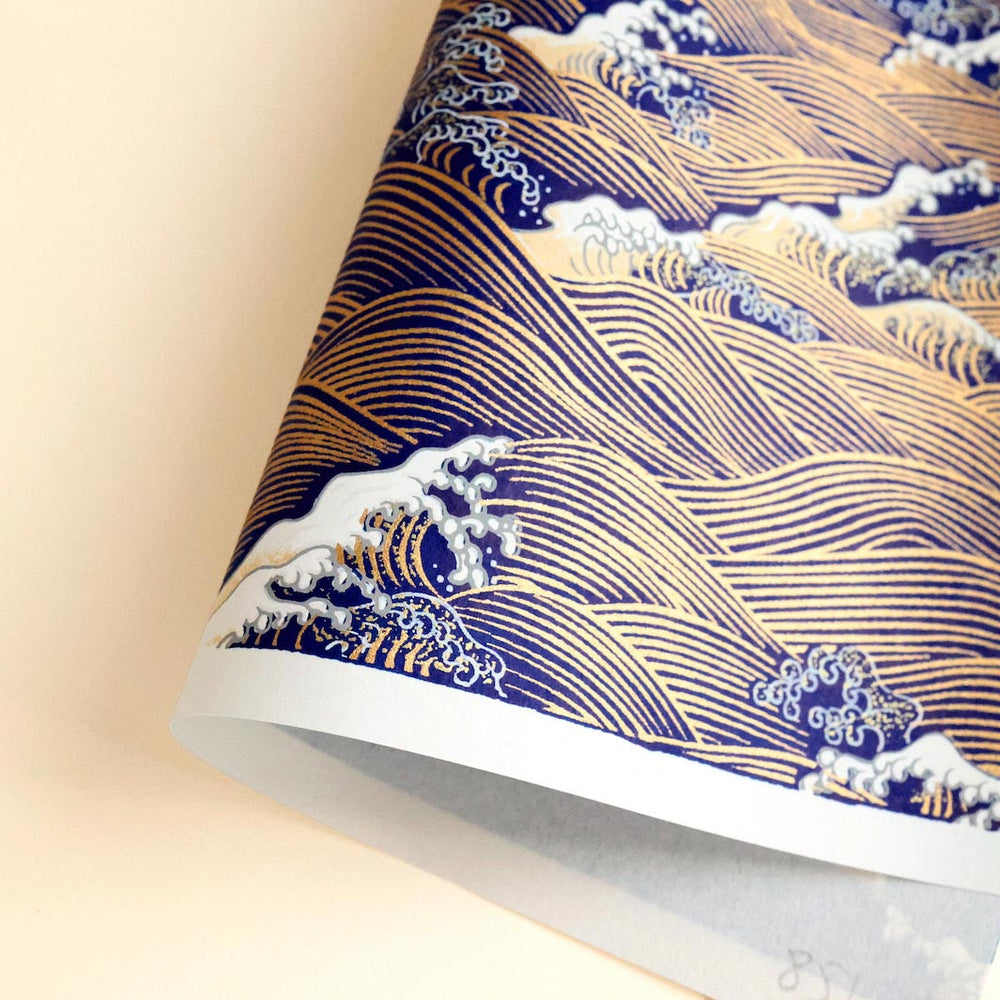 photo packshot d'une courbe de papier japonais yuzen chiyogami aux motifs de vagues et d'écumes dans les tons bleu nuit, jaune clair et dorés adeline klam (M851)