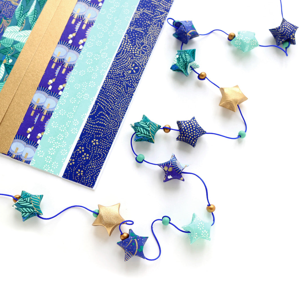 photo packshot d'un détail des étoiles du kit guirlande d'étoiles en origami bleu nuit, bleu turquoise, vert, vert d'eau et doré « libellule » adeline klam