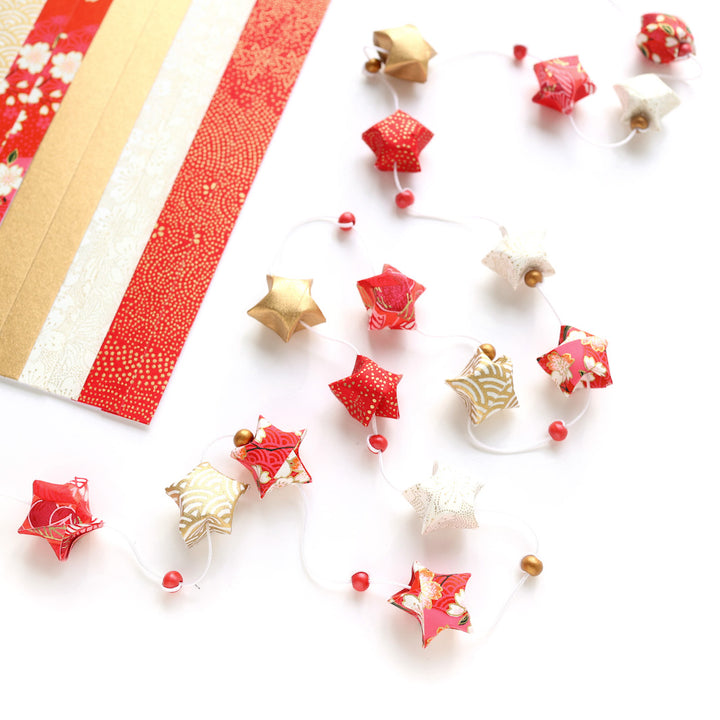 photo packshot d'un détail des étoiles du kit guirlande d'étoiles en origami rouge, orange, rose corail, blanc cassé et doré « poinsettia » adeline klam