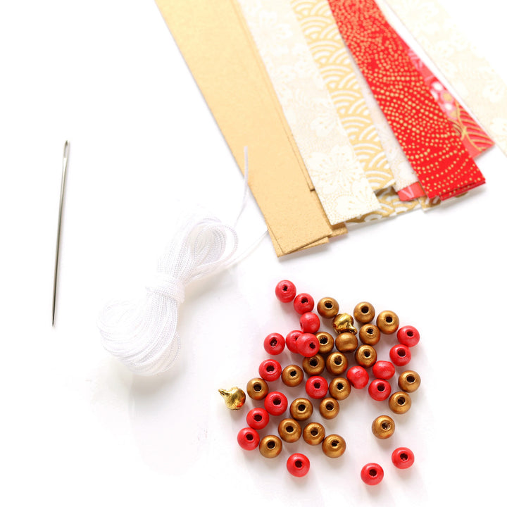 photo packshot d'un détail du matériel du kit guirlande d'étoiles en origami rouge, orange, rose corail, blanc cassé et doré « poinsettia » adeline klam