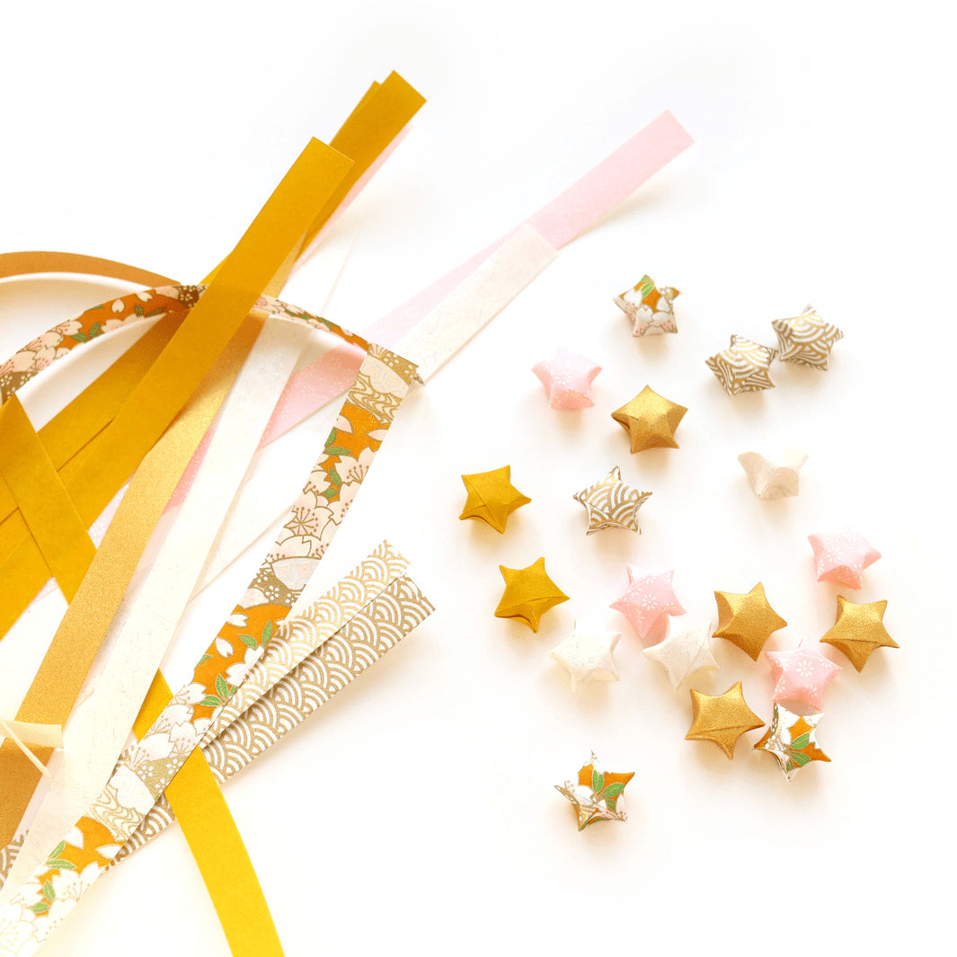 photo packshot des étoiles et des bandelette de papier japonais du kit guirlande d'étoiles en origami jaune moutarde, rose clair et blanc « savane » adeline klam