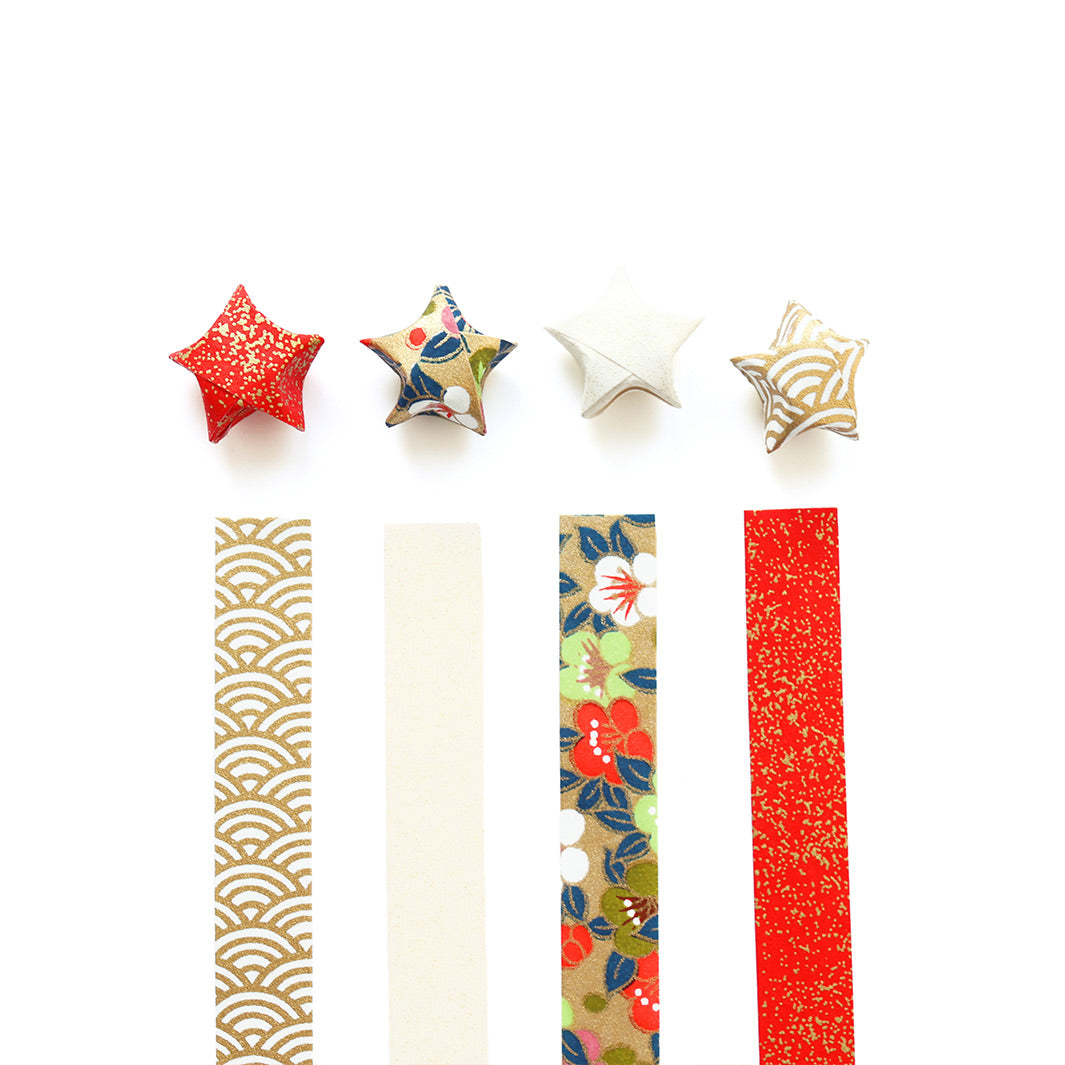 photo packshot des étoiles montées et des bandelettes de papiers japonais du kit étoiles en origami dans les tons dorés, rouges, blanc crème, verts et bleu foncé « festif » adeline klam