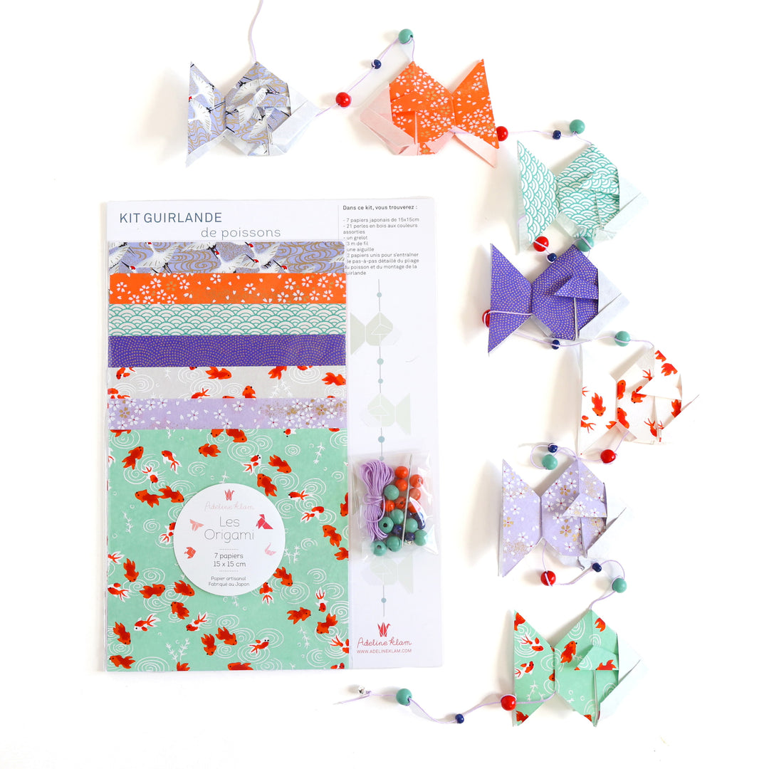 photo packshot de face du packaging et de la guirlande montée du kit guirlande de poissons dans les tons vert d'eau, rouge orange, blanc crème et violet mauve « fluorite » adeline klam