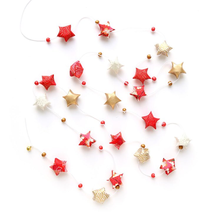 photo packshot de la guirlande montée du kit guirlande d'étoiles en origami rouge, orange, rose corail, blanc cassé et doré « poinsettia » adeline klam