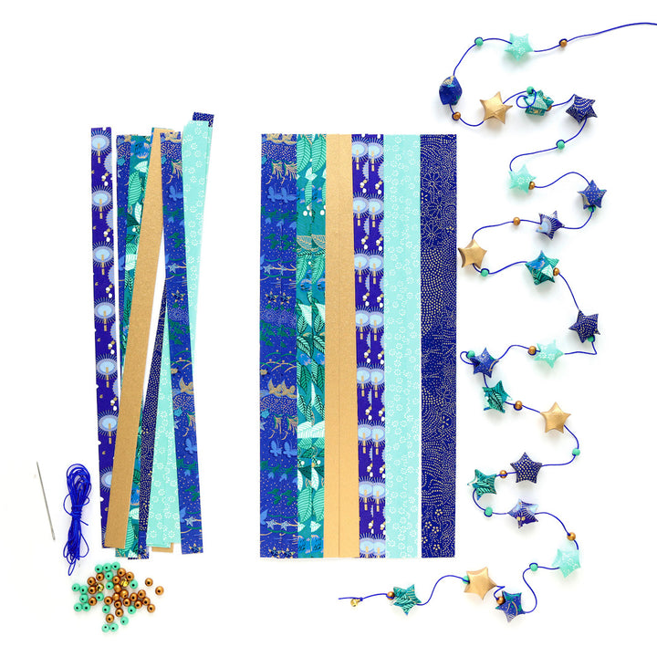 photo packshot de la guirlande montée et du matériel du kit guirlande d'étoiles en origami bleu nuit, bleu turquoise, vert, vert d'eau et doré « libellule » adeline klam