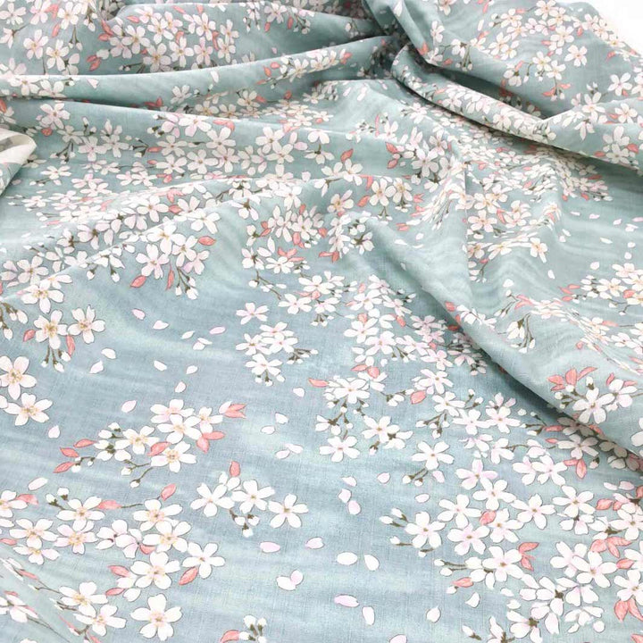 photo packshot du tombé du tissu japonais aux motifs de fleurs de cerisier dessinées dans les tons bleu gris, rose corail et blanc T551