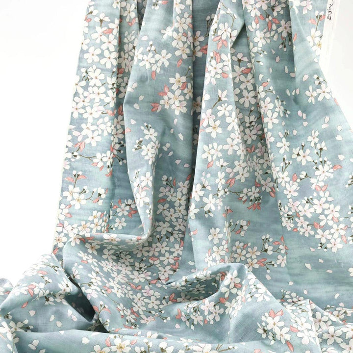 photo packshot du tissu japonais aux motifs de fleurs de cerisier dessinées dans les tons bleu gris, rose corail et blanc T551