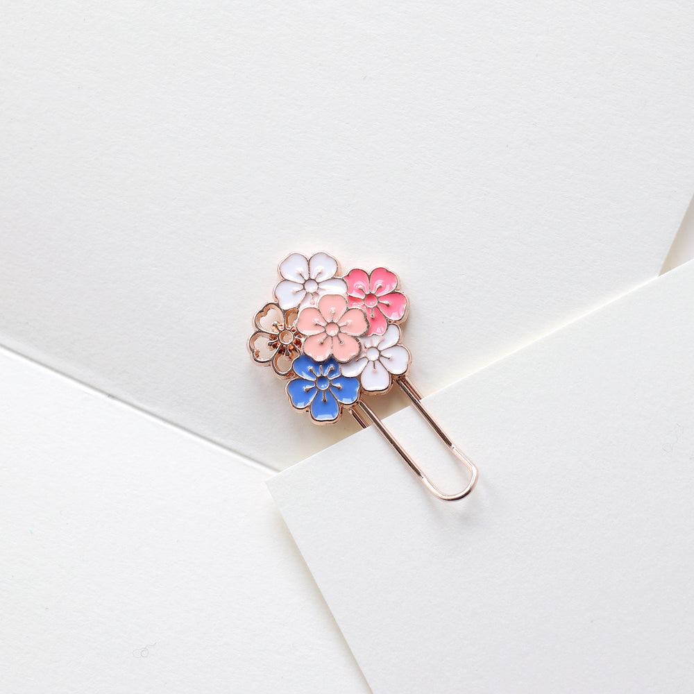 photo packshot de l'utilisation du marque-page trombone or rose décoré d'une grappe de fleurs de cerisier roses, blanches et bleues