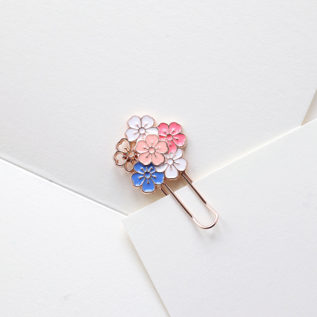 photo packshot de l'utilisation du marque-page trombone or rose décoré d'une grappe de fleurs de cerisier roses, blanches et bleues