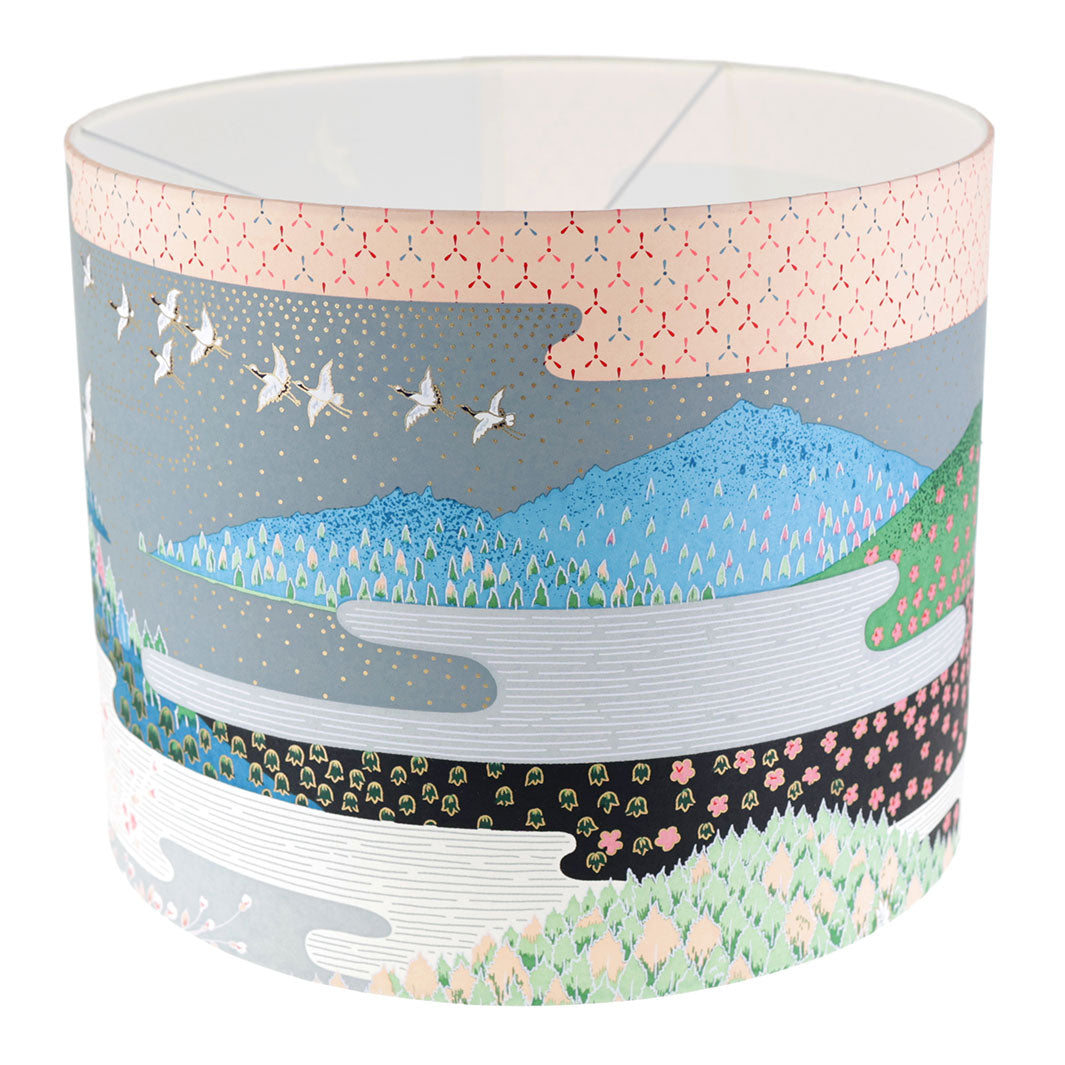 photo packshot avec une vue de face d'un abat-jour japonais au motif de paysage japonais (ciel et montagne) dans les tons bleus, verts, gris, noirs, orange et roses