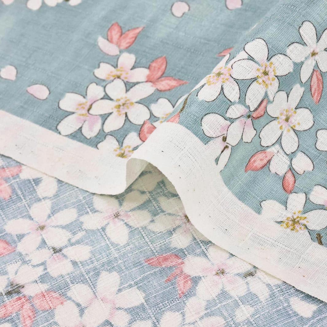 photo packshot zoomée d'un détail du tissu japonais aux motifs de fleurs de cerisier dessinées dans les tons bleu gris, rose corail et blanc T551
