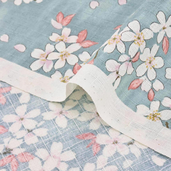 photo packshot zoomée d'un détail du tissu japonais aux motifs de fleurs de cerisier dessinées dans les tons bleu gris, rose corail et blanc T551