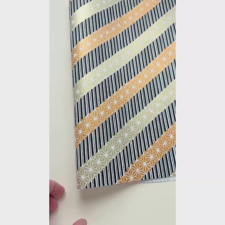 vidéo de démonstration du papier japonais yuzen chiyogami aux motifs de lignes épaisses et grandes étoiles dans les tons or clair, bronze et noir adeline klam (M1023)