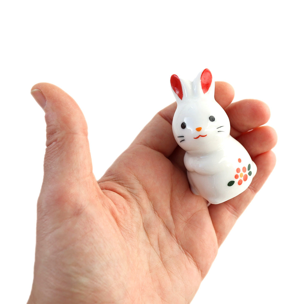 figurine de lapin blanc assis en céramique dans une main