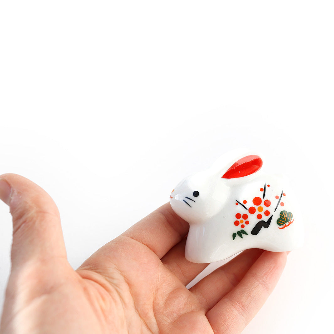 figurine de lapin blanc debout en céramique dans une main