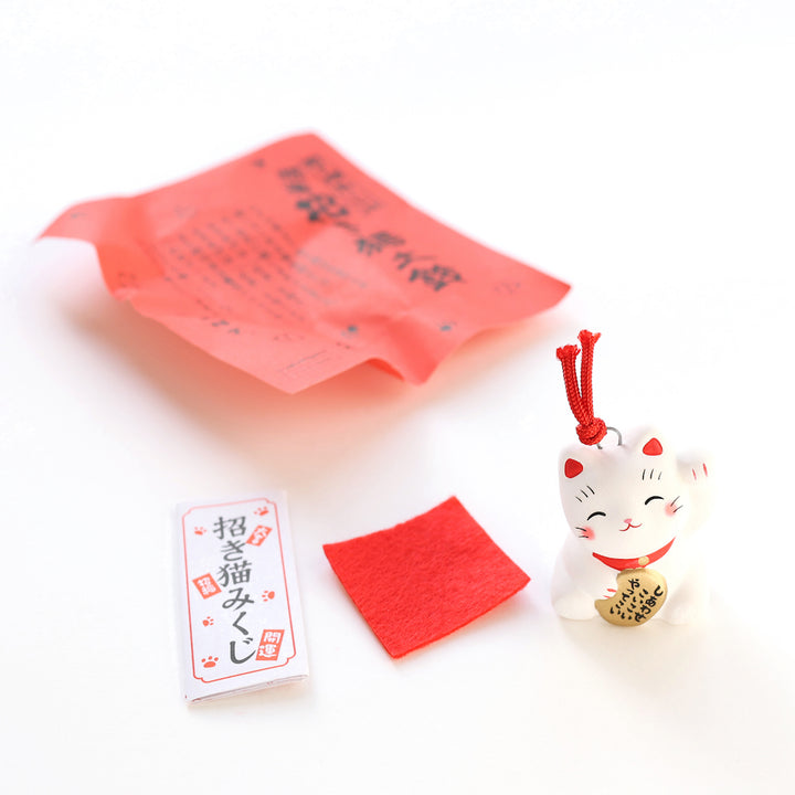 petit grigri grelot maneki neko blanc et rouge posé et prédiction porte-bonheur