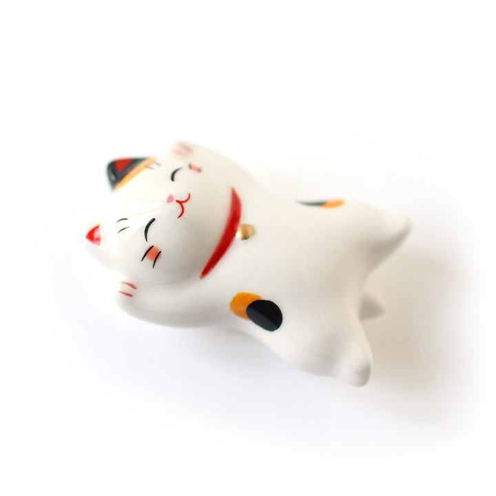 photo packshot d'un chat maneki-neko en céramique au pelage blanc moucheté de noir et de roux